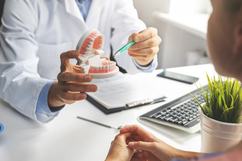 Dentist pointing to model of teeth in office