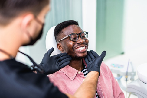 Dentist looking at patient's smile in treatment room