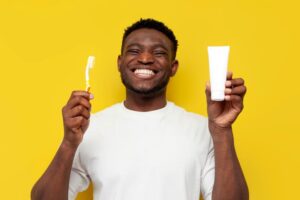 Young man holding toothbrush and toothpaste